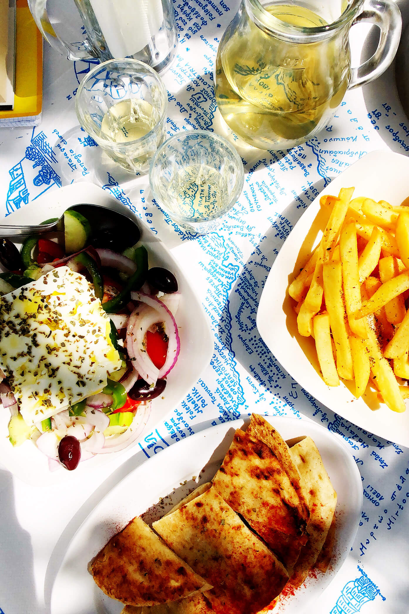 希腊Folegandros Souvlaki Club餐厅的希腊沙拉、皮塔饼、薯条和葡萄酒